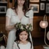 Bride adjusting a floral crown on a smiling girl in a white dress