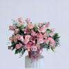 Pink roses and lilies arranged in a pink vase with ribbon