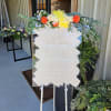 Floral sign topper with orange and yellow blooms and trailing greenery