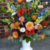 Large mixed flower arrangement in a white pedestal vase
