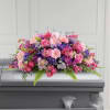 Pink and purple floral casket spray on a gray casket