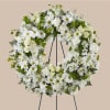 White floral wreath on a black stand with daisies and roses