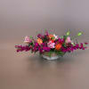 Low floral centerpiece with pink, orange, and magenta blooms in a white bowl vase