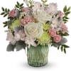 Pink and white flowers arranged in a green glass vase