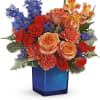 Mixed bouquet of roses, carnations, and blue flowers in a blue vase