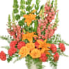 Orange lilies and roses with pink snapdragons in a vase