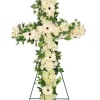 White floral cross on a stand with green foliage