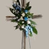 Cross-shaped floral arrangement with blue and white flowers on a wooden stand