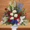 Red roses, white daisies, and blue flowers in a white vase