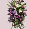 Tall standing floral spray with white lilies, pink roses, and purple blooms