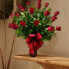 Red roses arranged in a black vase with a large red ribbon