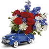 Blue toy truck filled with red, white, and blue flowers