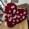 A heart-shaped wrapped bouquet made with roses in shades of red and