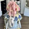Pink plush bunny sitting on a box of pink and blue flowers