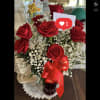 Arrangement of red roses and white filler flowers in a red glass vase with a red love ribbon