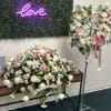 Pink and white floral arrangements with a neon love sign