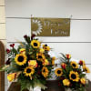 Two sunflower and rose arrangements in white containers on a table