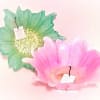 Two decorative glass flower-shaped bowls, one green and one pink