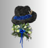 Black floral hat-shaped arrangement with blue ribbon and pale roses