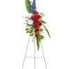 Standing floral spray with red roses, white blooms, and blue flowers on a metal easel