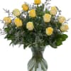 Yellow roses arranged in a clear glass vase with greenery