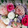 Standing spray of pink, white, and lavender roses with green accents