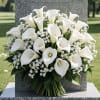 White calla lily funeral spray with baby's breath on a gravestone
