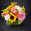 Mixed bouquet with roses, sunflowers, carnations, and pink daisies in a glass vase