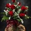 Deep red roses clustered with delicate white stock create a timeless dozen-rose