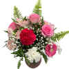 Pink roses, carnations, and a gerbera daisy in a round vase