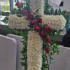 White floral cross on an easel with red roses