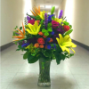 Tall mixed bouquet in a clear glass vase with bright lilies and roses