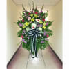 Tall standing spray of mixed colorful flowers with a large black and white bow on an easel.