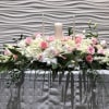 Pink and white floral centerpiece with candles on a table