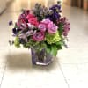 Pink and purple rose bouquet in a square glass vase