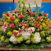 Large stage floral arrangement with pink roses, stargazer lilies, white hydrangeas and yellow flowers