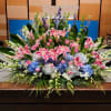 Large altar-style arrangement of pink lilies, blue hydrangeas, and white flowers in a fan shape