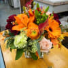 Mixed bouquet with orange lilies, gerbera daisies, and roses in a glass vase