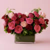 Pink and red roses arranged in a square glass vase