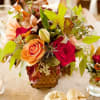 Autumn floral arrangement with red and peach roses in a small vase