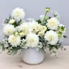 Low white arrangement of dahlias and mums in a white ceramic pot