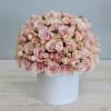 Dome of light pink roses arranged tightly in a round white hatbox-style container