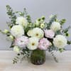 Low glass vase of white dahlias and pale pink lisianthus with airy greenery.
