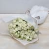 Large bouquet of white roses wrapped in striped white paper with a ribbon.