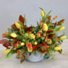 Low arrangement of yellow tulips and orange roses in a round white container
