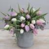 Pastel pink, white, and lavender tulips arranged loosely in a gray pot