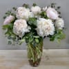 Layers of delicate light pink peonies spill over the rim of a