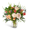 Mixed bouquet of cream, peach, and coral flowers in a clear glass vase