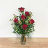 Red roses arranged in a clear glass vase with greenery