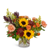 Mixed bouquet of sunflowers, roses, and carnations in a clear glass vase